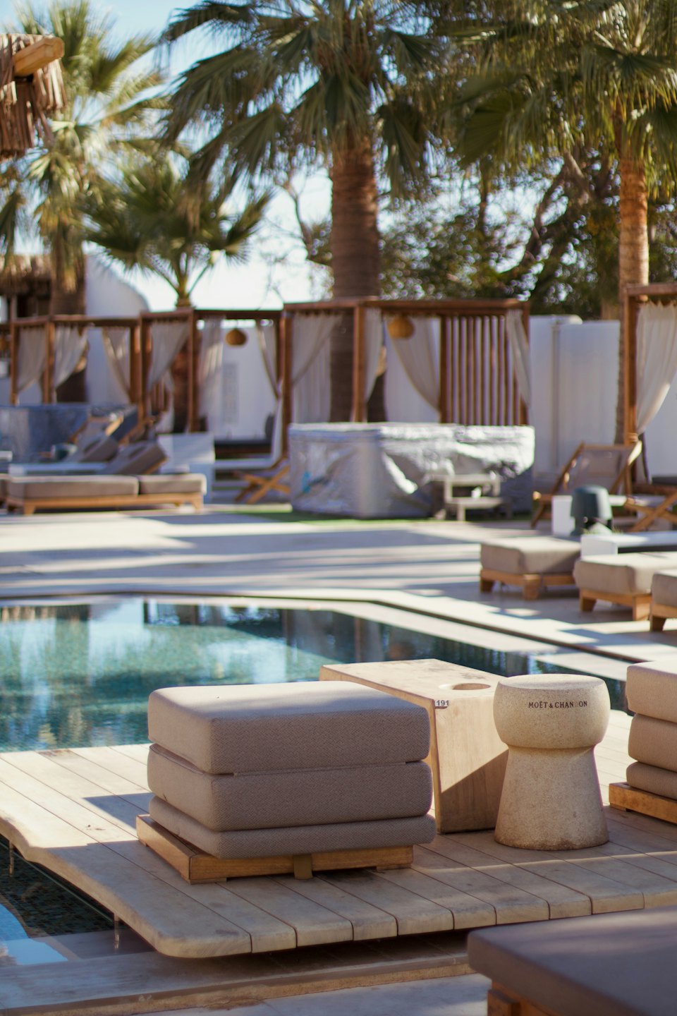 Terraza de piscina de resort moderno con tumbonas y palmeras.