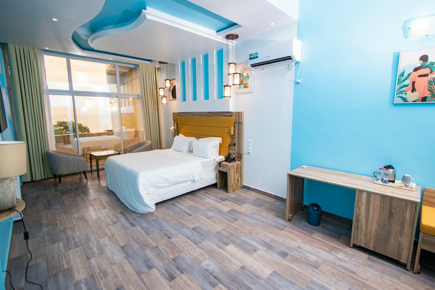 Habitación de hotel con cama queen y dos sillones grises.