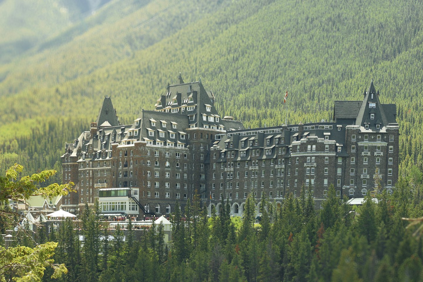 Hotel castillo enclavado en un denso bosque con montañas neblinosas.