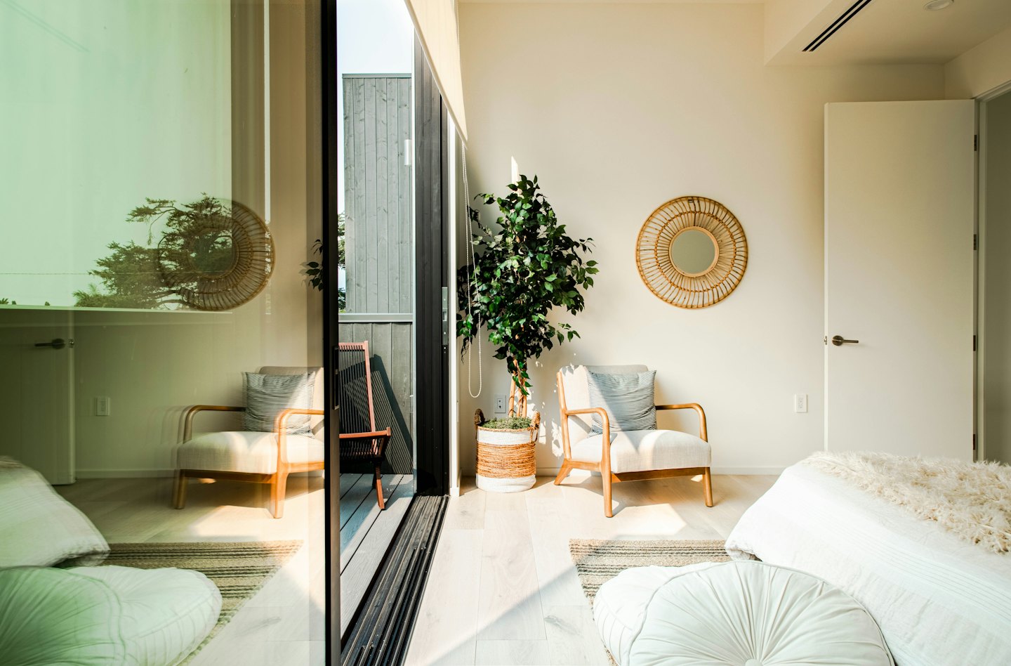 La luz del sol entra en una habitación moderna con sillones y una cama.