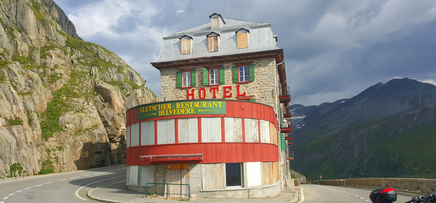 Un hotel de piedra de varios pisos se encuentra a lo largo de un camino de montaña sinuoso.